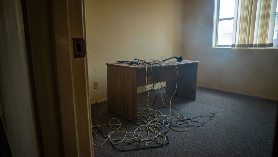 A home office before redesign, with grey office carpet and a cheap laminate desk